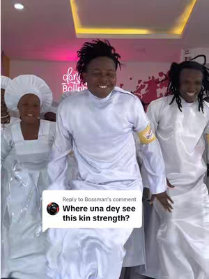 A group of people in white robes are dancing joyfully, with one person in the foreground smiling widely. The room has pink accents and a dance studio logo.