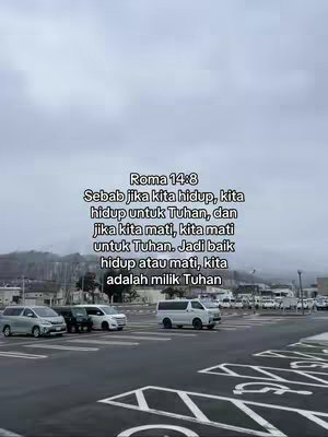 The image shows a parking lot with several cars parked. In the center of the image, there are large white text overlays with a quote from Romans 14:8, written in Indonesian. The sky is overcast, giving the scene a generally muted, neutral color palette.