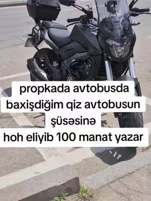 A picture of a black motorcycle parked on a gray and brown paved surface with a sign in front of the rider. Text in white is added on the image with the caption.