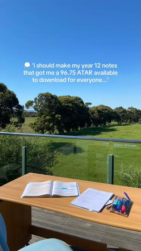 The image captures a sunny outdoor scene with a clear blue sky. A wooden table is set on a patio overlooking a green field and trees in the distance. On the table are an open book, several sheets of paper, and a pen case with markers. The text overlay suggests this is about sharing notes.