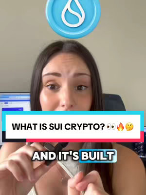 A woman with dark hair is framed from the chest up. She's holding a small object in her hands and looking towards the camera with a questioning expression. The background has a blurred office-like setting with various screens in the background and a coin with a drop-like logo above her.