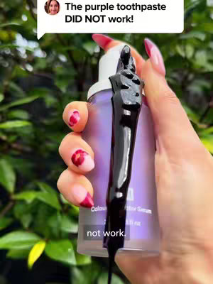 A person is holding a purple bottle of a product with a black fluid dripping from it. A speech bubble overlays the image containing text. Behind the person, there is lush green foliage.