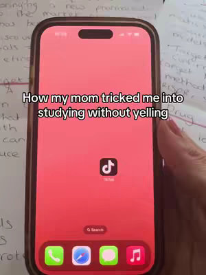 A phone displaying a red interface with a TikTok icon prominently displayed. The phone is held against a backdrop of handwritten notes on paper. Text overlay reads, 'How my mom tricked me into studying without yelling.'