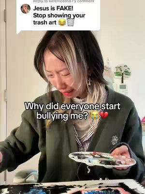 A selfie-style video cover image featuring a woman with blond and dark hair, looking down with a sad expression. Text overlays indicate the user is being bullied. Background shows a room and painting supplies. 