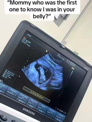 An ultrasound image displayed on a black medical device. The image shows a developing fetus inside a dark anatomical view. Above the screen is a text overlay with a question.