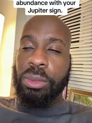 The cover image is a close-up shot of a Black man. The man has a shaved head and a full, dark beard. His eyes are closed, and he has a neutral expression. Behind him, there are blinds and a wall, as well as a photo in a frame.