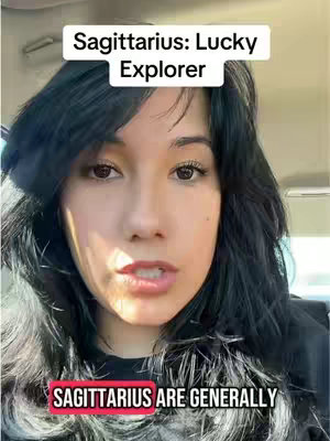 The cover image is a selfie-style shot featuring a woman. Above her head is a white rectangular text box containing the words "Sagittarius: Lucky Explorer" in black text. At the bottom, a red rectangular box states "SAGITTARIUS ARE GENERALLY" in white, bold, capital letters. The woman's face fills most of the frame, with dark hair framing her face and shoulders. She appears to be speaking. The background is blurred, with glimpses of car interior.