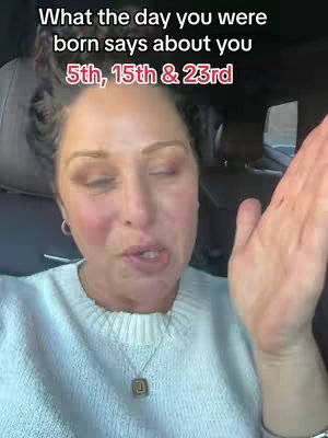 A woman is shown in a selfie-style video, sitting inside a car. She is looking at the camera and gesturing with one hand, with text overlays at the top discussing numerology and birthdates.