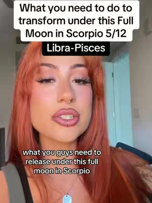 A selfie-style shot of a woman with auburn hair, full lips, and facial piercings. She is looking at the camera with a serious expression. Text overlays at the top and bottom provide context about astrology and releasing energies under the full moon.