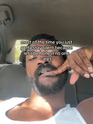 The video cover shows a dark-skinned man in a car, looking toward the camera. Above him, text overlayed in capitalized white sans-serif font reads, “most of the time you just gotta stay silent because let’s be honest no one cares.” The man’s hand is raised to his face, with his index finger touching his lip and indicating his teeth and mouth which are slightly open. He is wearing a white tank top.