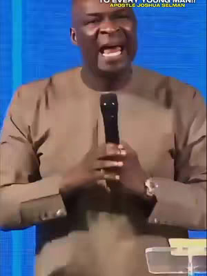 A man in a brown shirt stands in front of a blue background with a microphone in his hands. Text overlays at the top of the image.