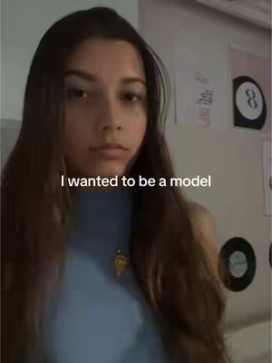 A young woman with long, dark hair is centered in the frame, looking towards the camera. The background includes a few decorations and items, with the text overlayed 'I wanted to be a model'.