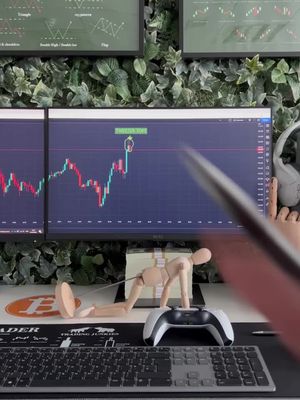 The image showcases a trading setup. A desk is visible with a computer monitor showing financial data (candlestick chart). There is a wooden mannequin appears to be pulling a bundle of fake cash, a gaming controller, and keyboard.
