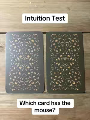 The cover image presents two tarot cards displayed side by side against a wooden background. The faces of the cards, which are the backs, feature a repeating floral design in tones of gray and green. The top and bottom of the image have text overlays with different white text.