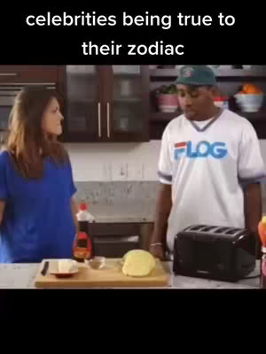 The image shows a kitchen scene with two people, a man and a woman facing each other as if in conversation. On the counter is a toaster, breakfast items, and a bottle of syrup. The text overlayed on the top reads 'celebrities being true to their zodiac.'