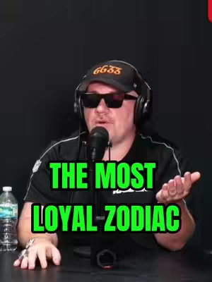 A man wearing sunglasses, a black cap with the text GG33, and a headset is speaking into a microphone. Text overlayed in the image reads 'THE MOST LOYAL ZODIAC.' The background is black, with bottles of water on the left side.