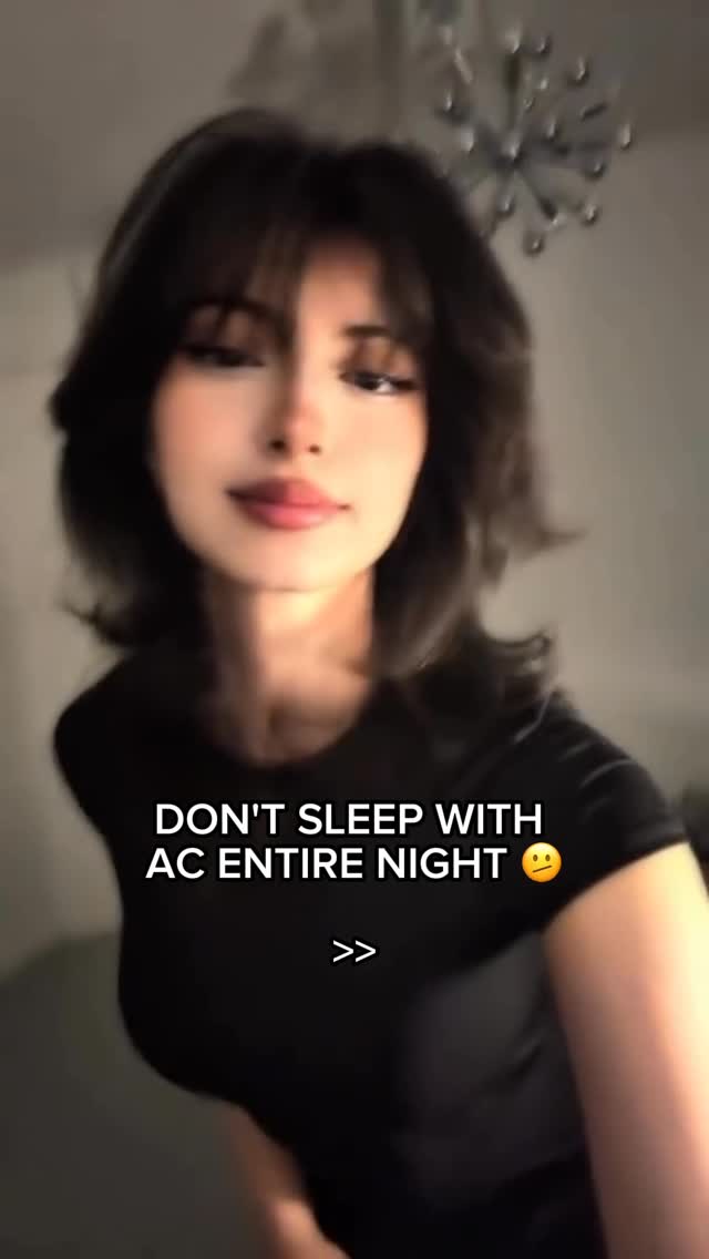 The cover image features a woman in a close-up shot, with text overlayed. She has shoulder-length dark hair with bangs. She is wearing a black top. The background is blurred, showing a room with a light fixture. The text overlay reads, "DON'T SLEEP WITH AC ENTIRE NIGHT," with an emoji.