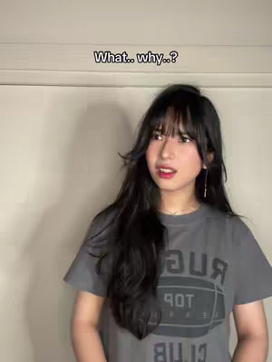 A young woman with long, dark hair and bangs is looking off to the side with a concerned expression in front of a plain background. A text overlay states: "What.. why..?"