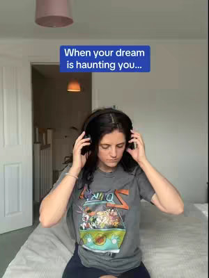 A woman is sitting on a bed and putting on headphones. Above her head is a text overlay in a blue rectangle that says, "When your dream is haunting you..." The background is a simple bedroom setting.