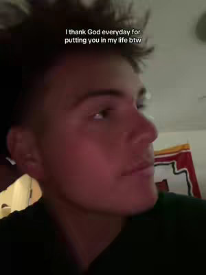 A medium shot shows a young man from the chest up with his face turned to the side, looking slightly upward. He's in a room with soft, warm lighting. The text overlay reads, "I thank God everyday for putting you in my life btw."