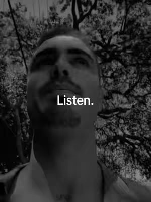 A grayscale selfie depicts a man from the chest up, set against a blurred background of tree branches. The man's gaze is directed upwards, with "Listen." overlaid in white text near his chin. The overall palette is monochromatic, giving a candid, yet serious impression.