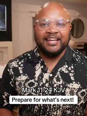 A man with glasses smiles at the camera. Text overlay is present at the bottom. The man is in a well-lit room, and a portion of a black TV is visible on the left.