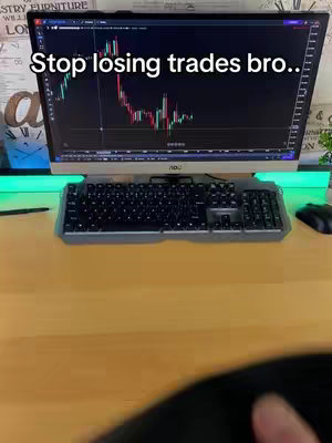 A computer screen displays a real-time stock market chart. The screen is the central element, with a keyboard and mouse in the foreground. The background shows a wooden desk and a wall with decorative elements.