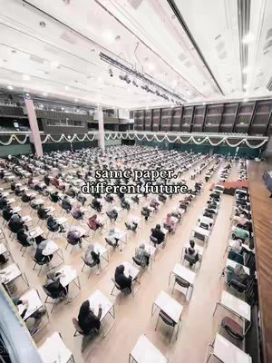 An aerial view of a large exam hall filled with students seated at desks. The hall is well-lit, with rows of desks neatly arranged. Text overlayed on the image reads, 'same paper, different future.'
