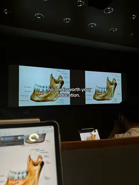 The cover image shows a screenshot of a lecture hall with two screens presenting a diagram of a jaw, and the text overlay. The foreground has a tablet with the same anatomical diagram. The image is dimly lit, suggesting a classroom lecture setting.