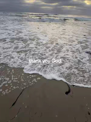 A serene beach scene with waves gently washing onto the shore under an overcast sky. The sand is wet and detailed. The text "thank you God" is overlaid on the image.