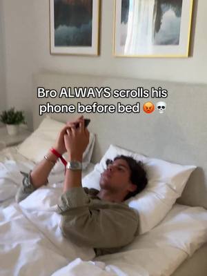 A man is lying in bed, holding a phone, with text overlayed. The framing is from a medium angle, capturing the upper body of the person who is lying on a pillow with white sheets and covers. Two framed pictures can be seen in the background.
