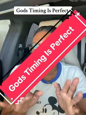 An interior car shot featuring a person inside. In the center is a tilted, red rectangular text overlay with the words 'Gods Timing Is Perfect' written in white. Above the overlay, a smaller white text reads the same. The person is wearing a white shirt with a blue collar and a Disney Mickey Mouse graphic, and is holding their hands out, visible in the bottom frame.