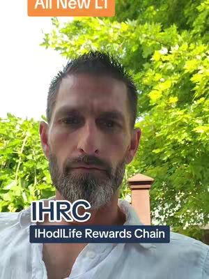 A man with short dark hair and a beard framed by a lush green natural background stands in front of a neutral background. He's wearing a white shirt, with the logo of IHRC and "I HodlLife Rewards Chain" in the middle of the frame, and above him, the text "All New LT" occupies the top-left.
