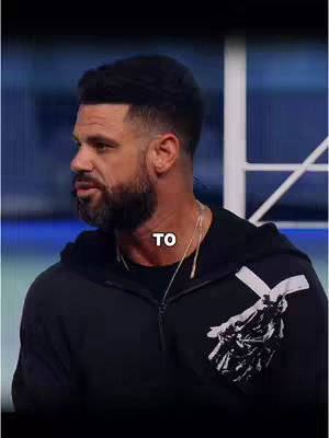 A man with a beard and dark hair is seen from the side, looking towards the left. He is wearing a black hoodie with some white and black design on the front. The word "TO" is overlaid on the image in a white font.