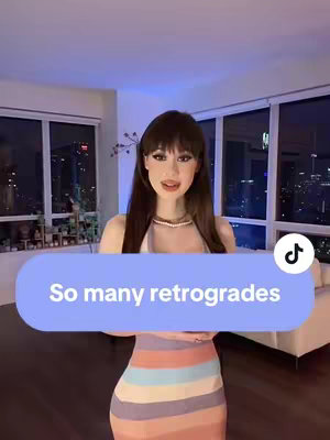 The cover image shows a woman in a room with a cityscape visible through the windows in the background. She is wearing a colorful dress and her bangs are styled across her forehead. There is text overlayed with a blue bubble that reads: So many retrogrades. The TikTok logo is in the bottom right corner.