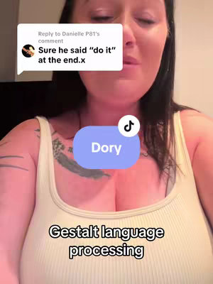 A woman is seen from the chest up, wearing a light yellow tank top. Text overlays include a comment bubble, a circular TikTok icon with the name "Dory", and the phrase "Gestalt language processing". The background is blurred, with the woman's face slightly visible, appearing to be in an emotional state.
