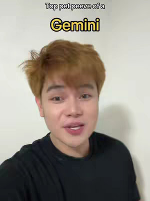 A young man with light brown hair is centered in the frame, speaking. Above him, the text overlay reads 'Top pet peeve of a Gemini' in white and yellow bubble font. He wears a black top against a plain off-white background.
