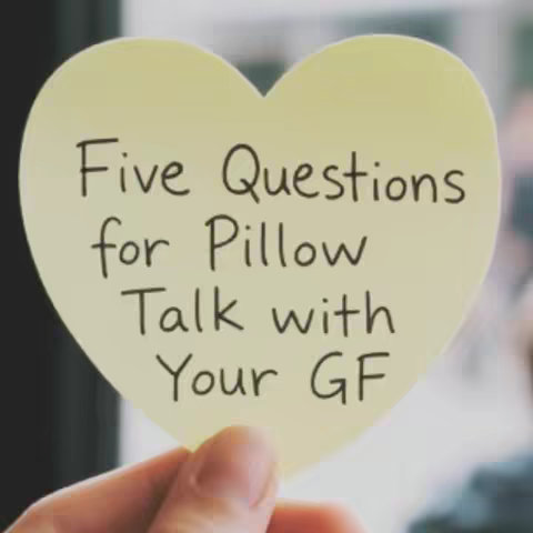 A hand holding a heart-shaped yellow sticky note. The note has the handwritten text: "Five Questions for Pillow Talk with Your GF."