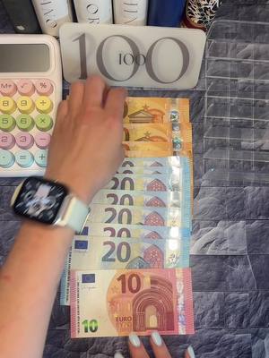A top-down shot features a hand holding several euro banknotes. There are five 20 euro notes and one 10 euro note. The person is wearing a smartwatch with a light blue band. The background shows some white bottles and a calculator.
