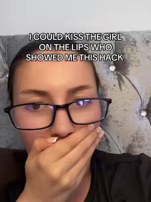 A selfie-style shot featuring a woman in a close-up. She wears black-framed glasses and covers her mouth with her right hand. The background appears to be a plush, textured headboard. The text overlay reads: “I COULD KISS THE GIRL ON THE LIPS WHO SHOWED ME THIS HACK.”