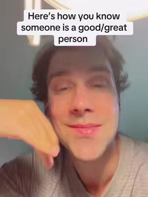 A selfie-style shot focusing on a man's face. He has short, dark hair and is wearing a light-colored shirt. The background has an out-of-focus area with lights. A text overlay provides the video's hook.