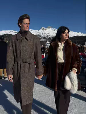 A couple holding hands while walking on snow, in front of some mountains.