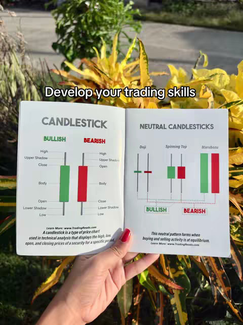 A person's hand holding open a book with candlestick charts displayed on both pages. The background includes a blurred view of outdoor plants. The text 'Develop your trading skills' is a hook overlay on the image.