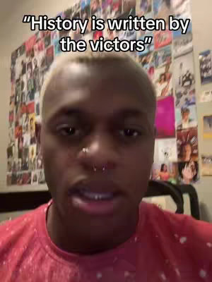 A selfie-style video shows a young man with short, bleached blonde hair and multiple facial piercings. He is wearing a red shirt. Behind him is a wall covered in a collage of images. Superimposed above his head is the text: "History is written by the victors".