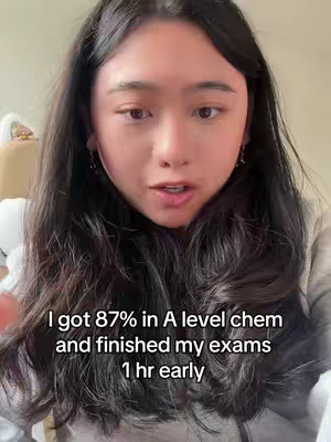 A selfie-style video with a young woman in the center, facing the camera. She has long, dark hair and is wearing what appears to be a light-colored top. The background is a blurred interior. The hook text is overlaid at the bottom, giving information about her exam results.