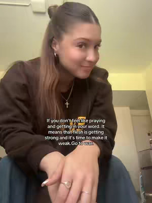 A young woman with her hair in a high bun looks towards the right, smiling. She wears a brown top and a necklace with a cross pendant. Text overlays in the bottom left corner provide words of inspiration.