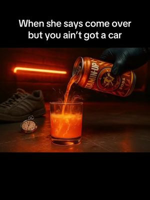 The image is set indoors with a dark, stylized aesthetic. The focus is on a glass being filled with bright orange liquid pouring from a can of Vitamin-Up soda. A pair of gray sneakers and a stopwatch are visible in the background, alongside an orange neon sign.