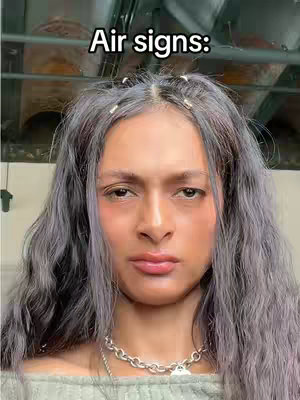 A selfie-style shot featuring a person with fair skin and long, wavy grey hair. The person is looking directly at the camera with a neutral expression, slightly pursing the lips, suggesting the rbf. The upper body is visible, wearing a sage green sweater. The background is out of focus, and text in a bold font is placed at the top of the frame. The overall composition is a close-up view that centers on the face to emphasize expression.