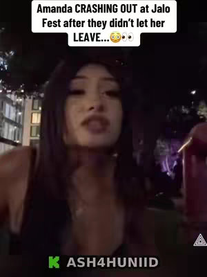 A selfie-style video cover image featuring a young woman looking at the camera with a somewhat shocked or surprised expression. She has long, dark hair and is positioned in front of a blurry urban background, likely an outdoor concert or festival environment at night. Overlaid on the top part of the image is a white banner with the text "Amanda CRASHING OUT at Jalo Fest after they didn't let her LEAVE..." in black, with the addition of several emojis. At the bottom left, a logo "KASH4HUNIID" is visible in green. The overall impression suggests drama and possibly a negative experience in a social setting.