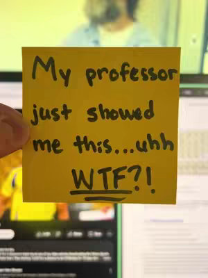 A hand holds a yellow sticky note against a background showing a computer screen and a person in the background. The sticky note has handwritten text on it.